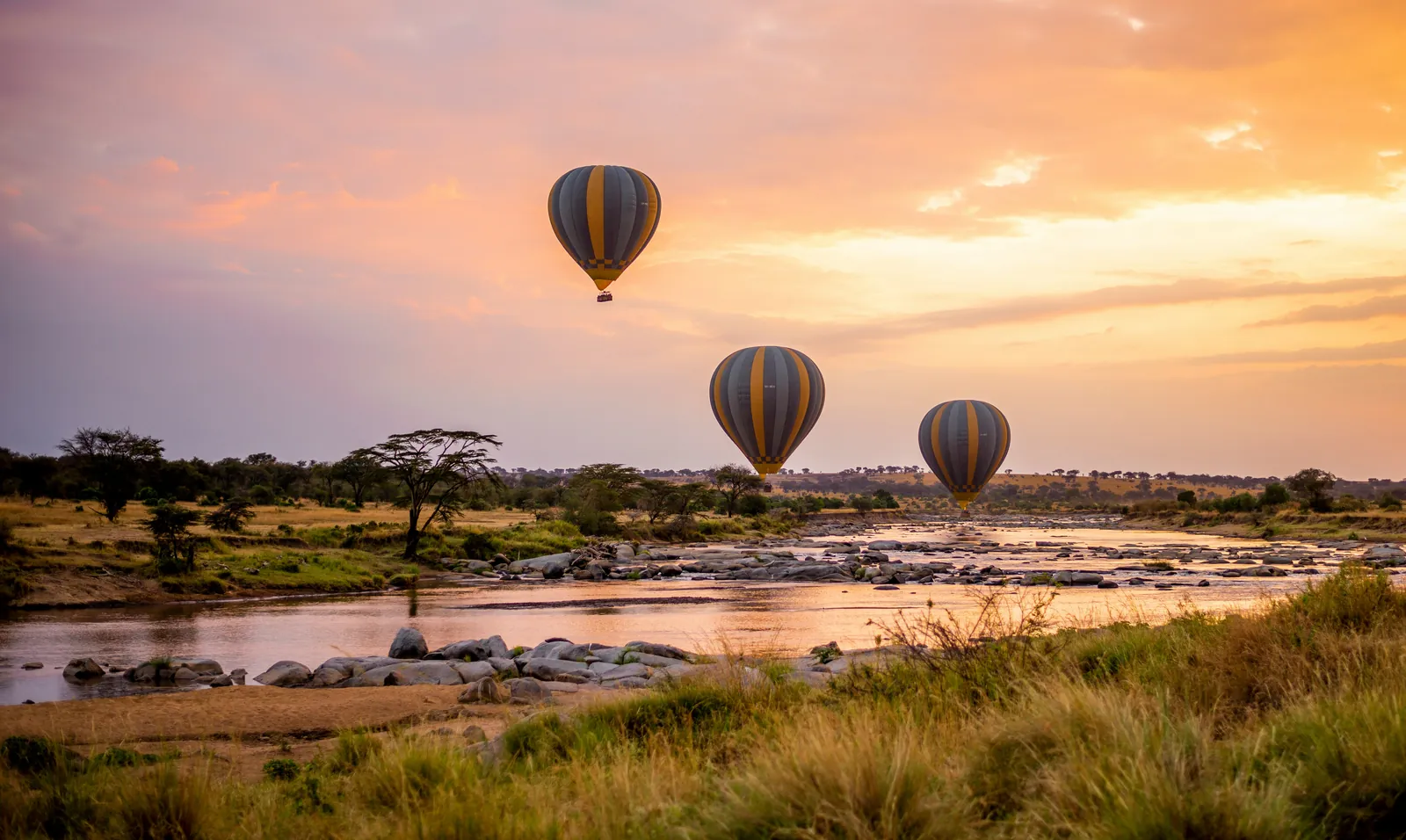 Balloons over a river in the Serengeti at sunrise