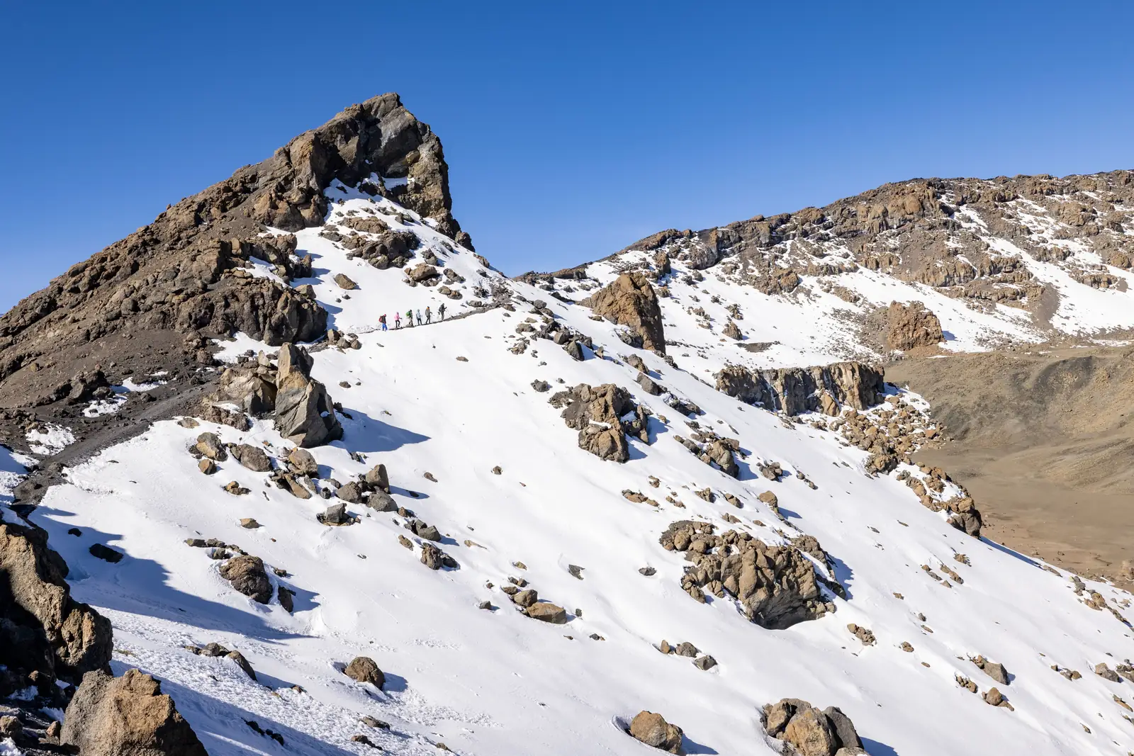 Hikers crossing the snowy crater rim